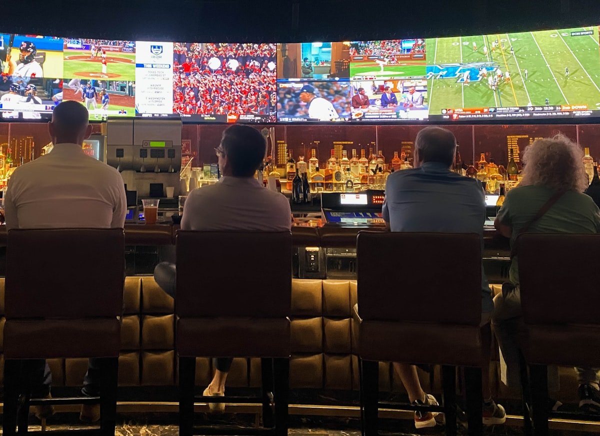 Guests seated at the bar counter watching live sport on TV
