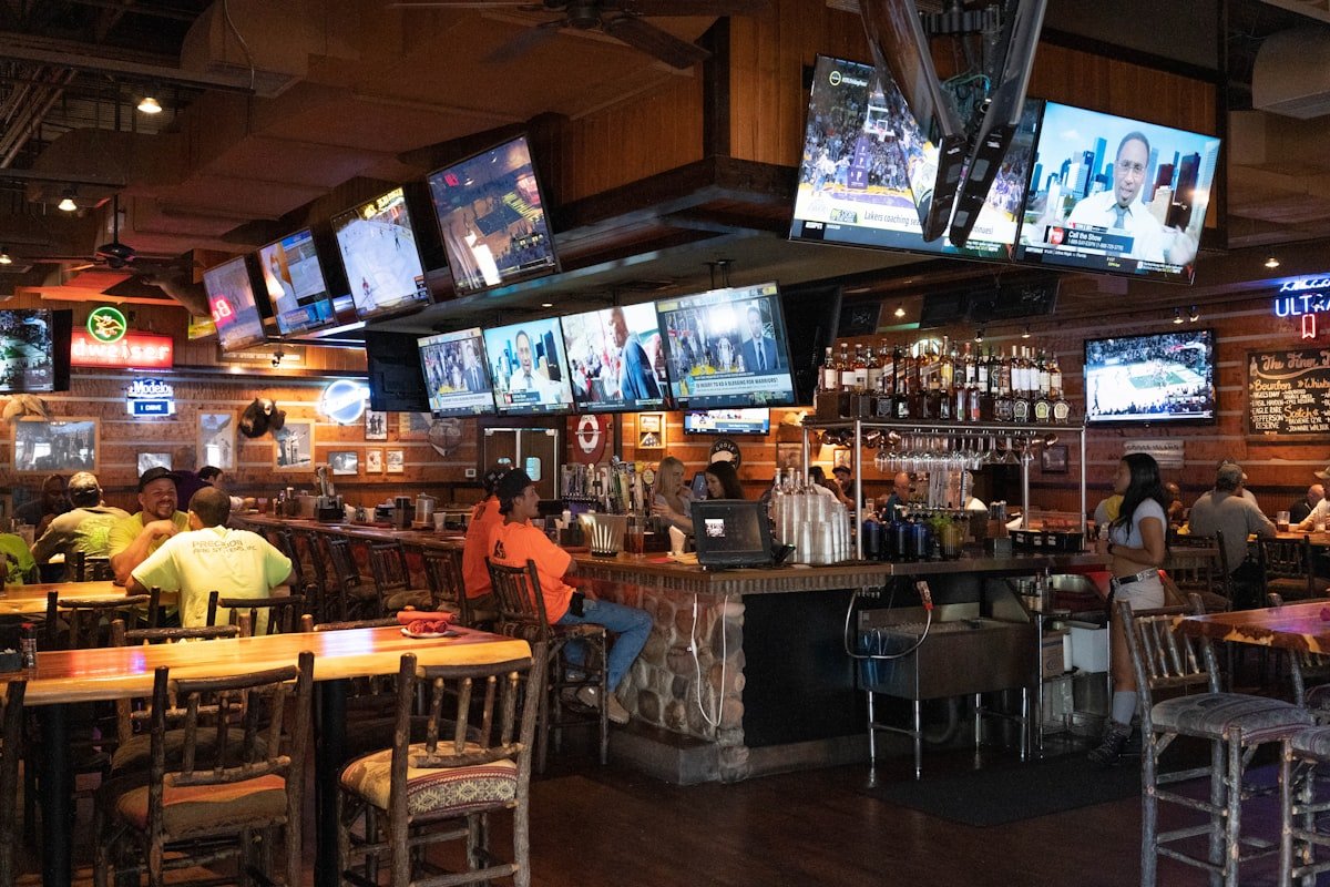 Group of fans gathered around a bar watching multiple screens
